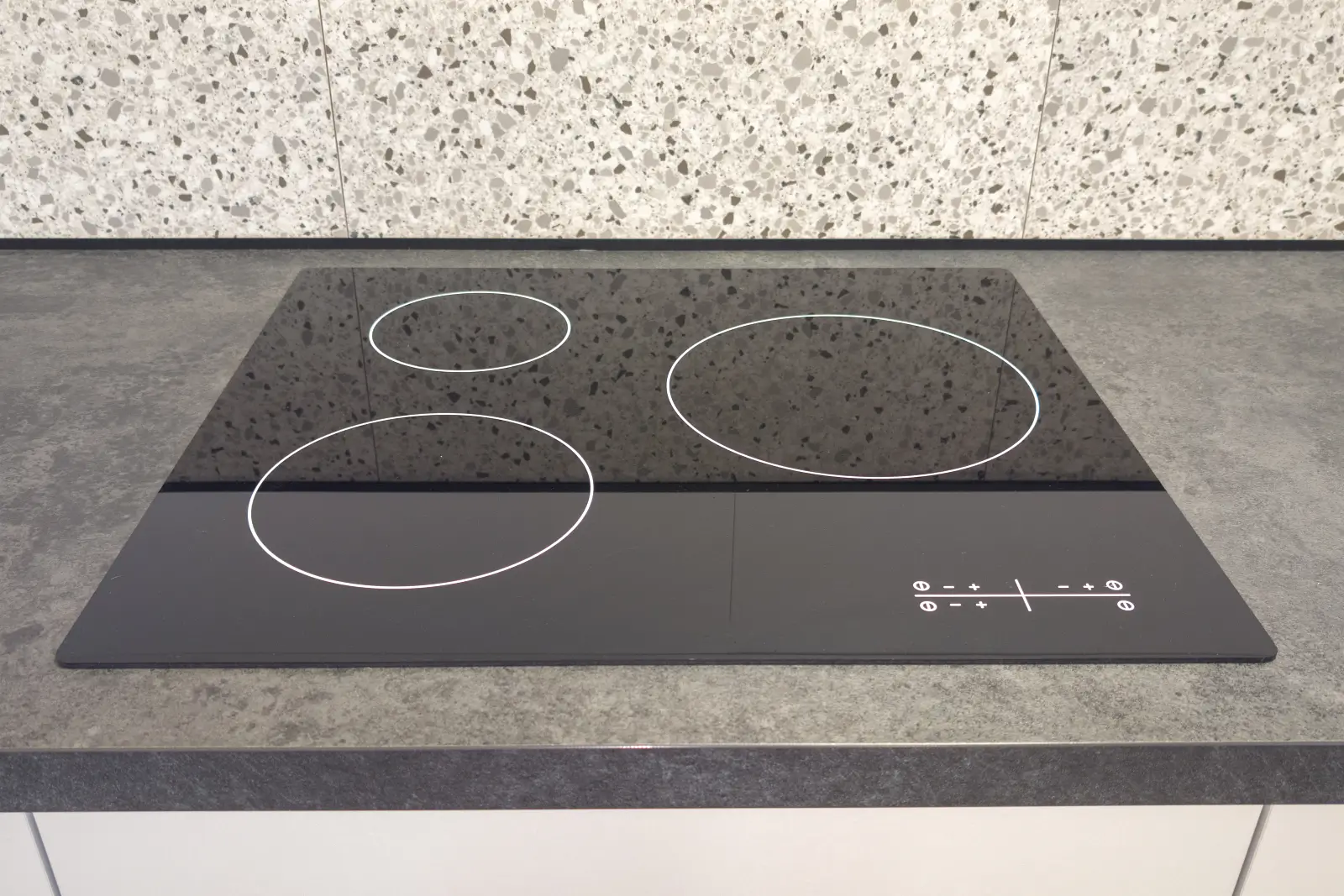 Flush-mounted black induction cooktop with touch controls in a modern kitchen countertop