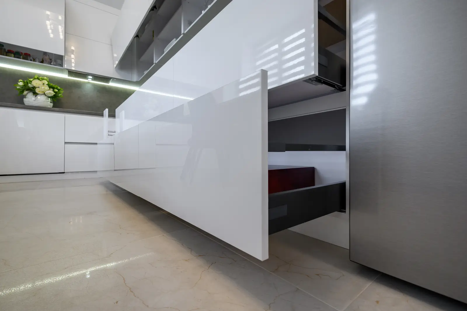 Glossy white flat-panel kitchen cabinets with push-to-open drawers in a modern minimalist interior